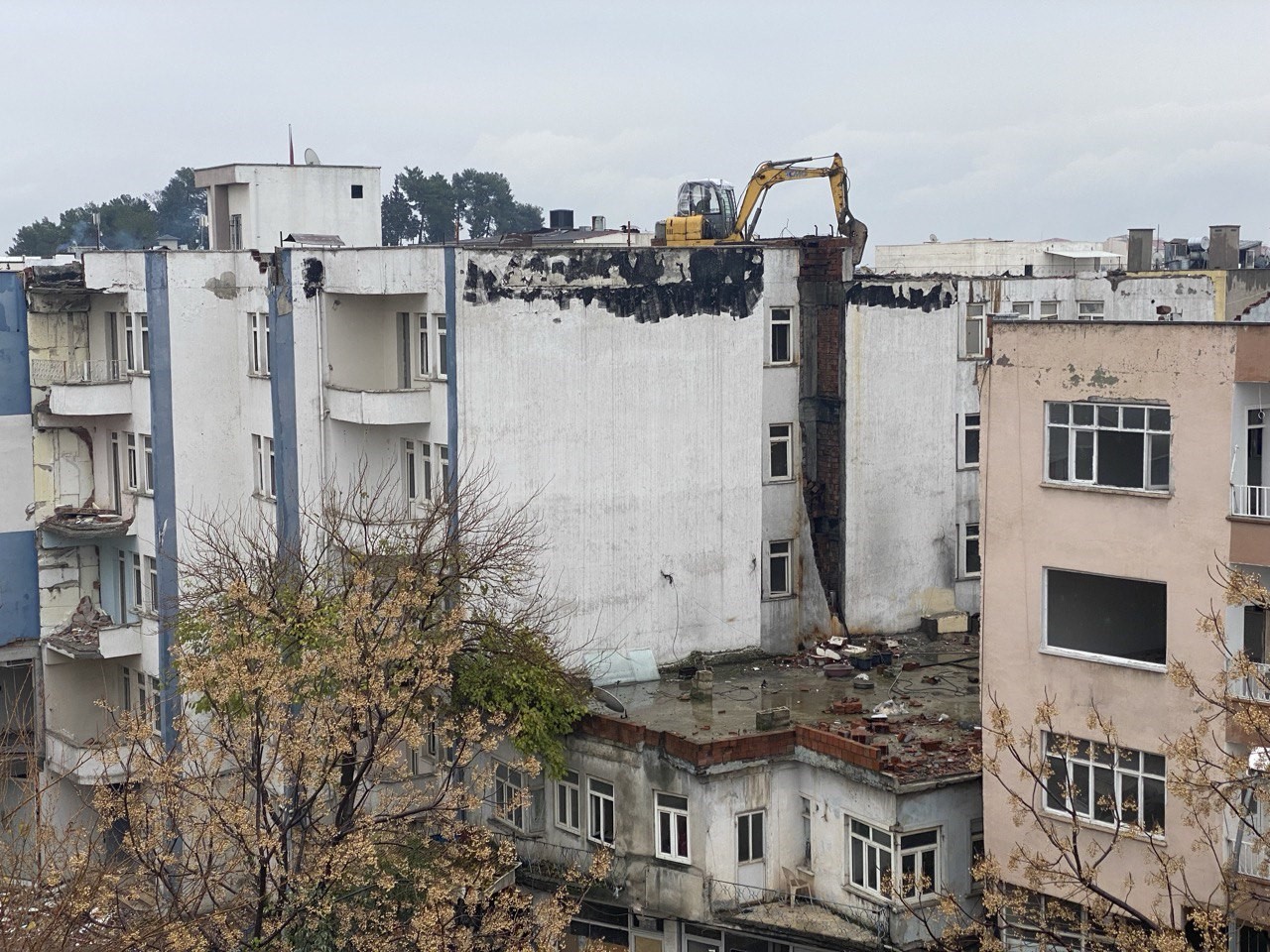 İş makinesi, ağır hasarlı bir binanın üzerinde yıkım işlemi için kullanıldı